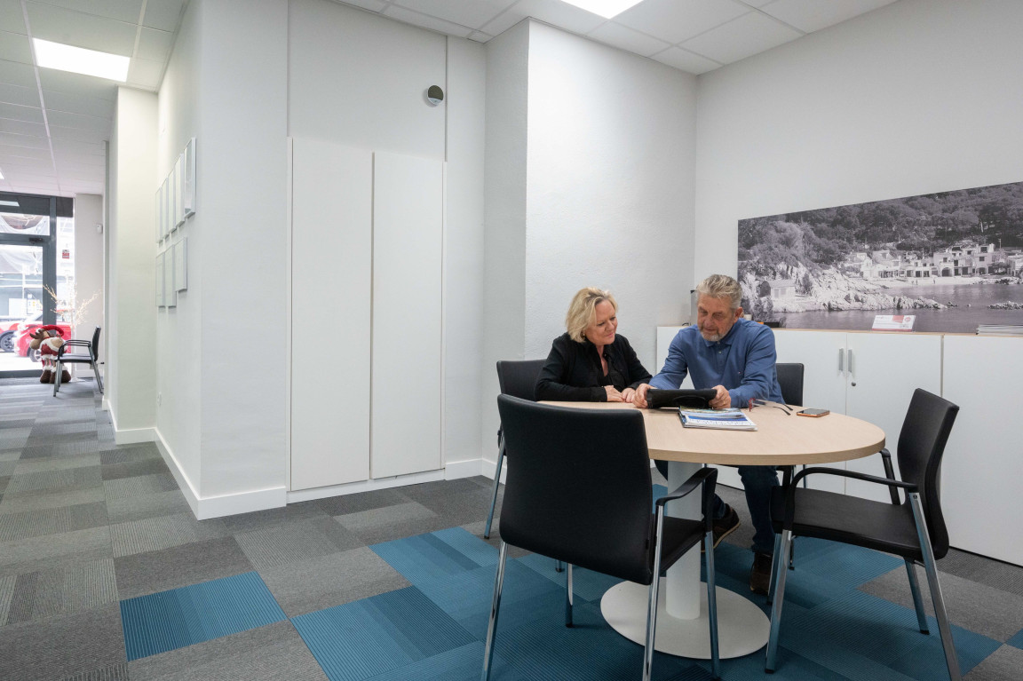 Two people meeting at a round table in the offices of Real estate agent Porfinca.