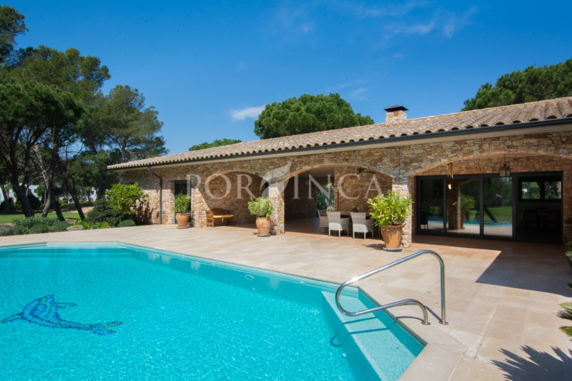 Natural stone facade of villa with swimming pool and large terrace.