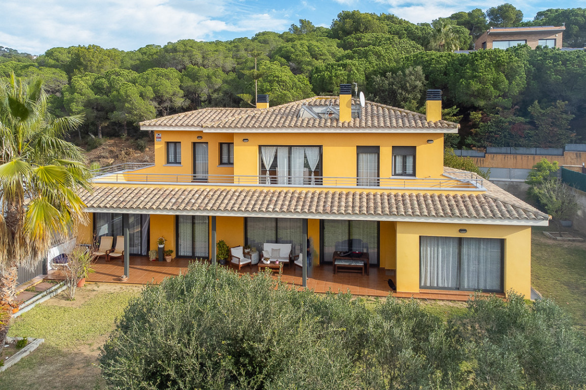 Facade of ochre-colored villa with covered terrace in wooded area in Sant Daniel, Sant Antoni de Calonge.