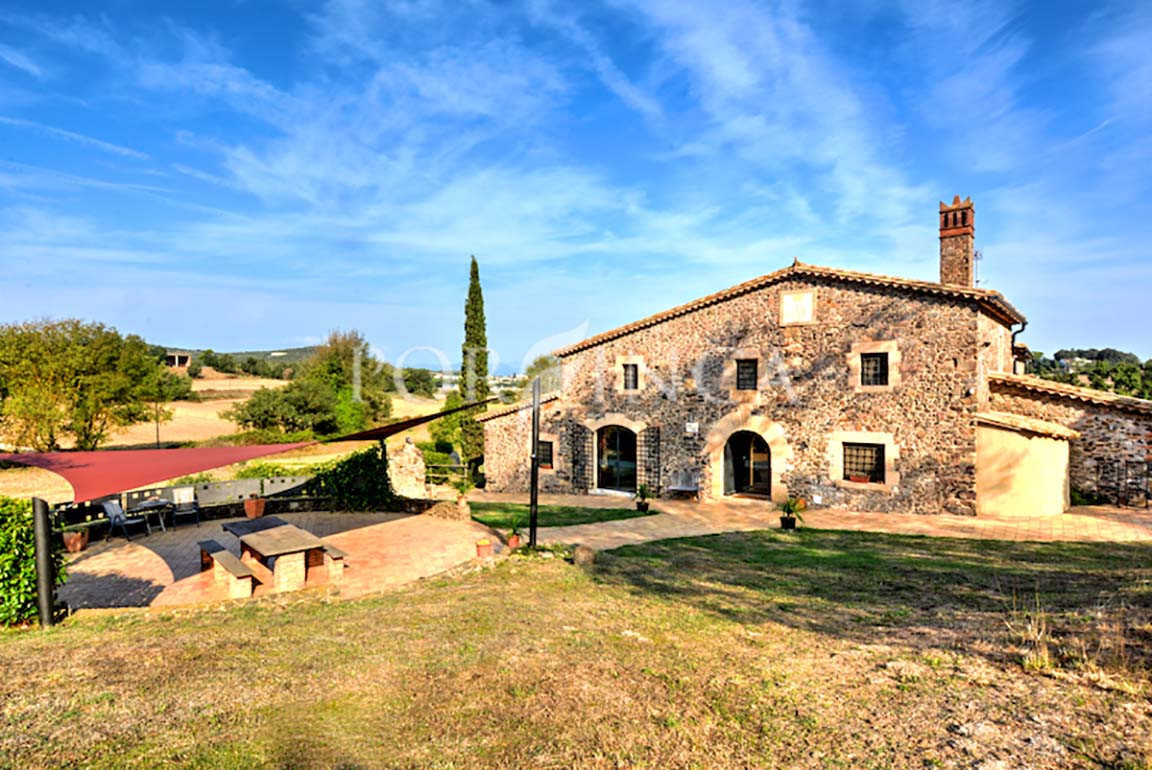 Countryhouse with covered terrace in front under blue sky in Llagostera.